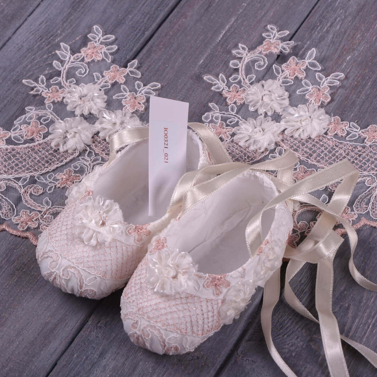  Christening Booties with ribbons on a wooden surface with lace details.