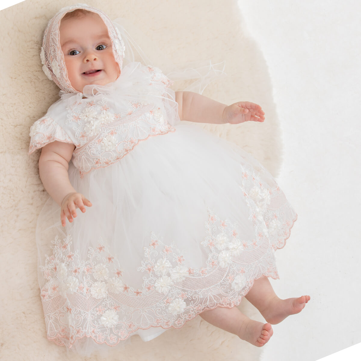 Baptism Dress with Floral Lace lying on a white surface