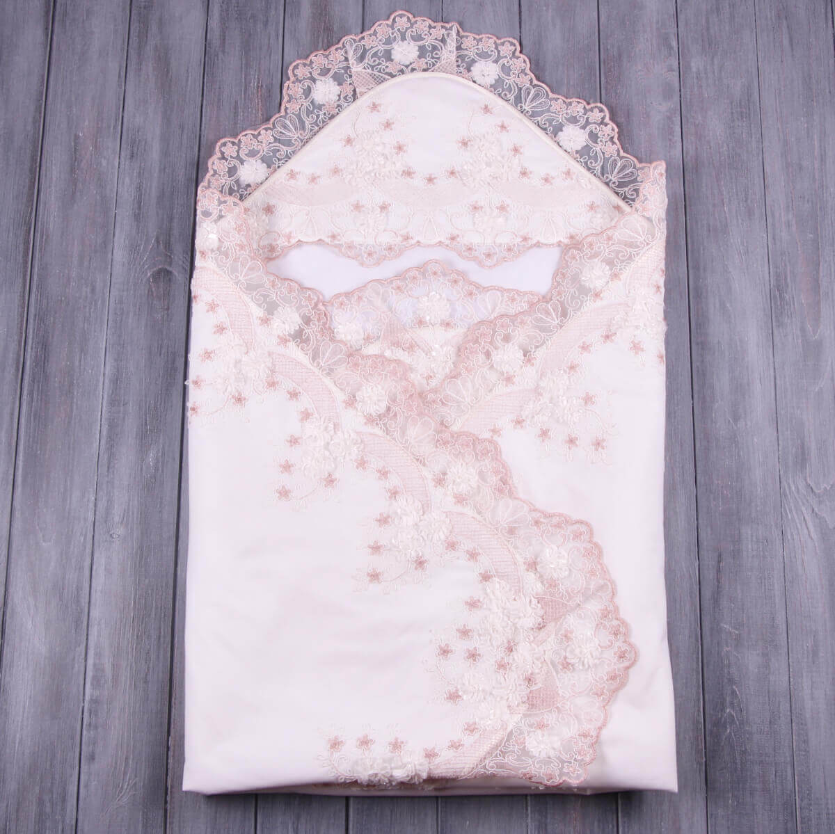 Folded lace baptism blanket on a wooden surface
