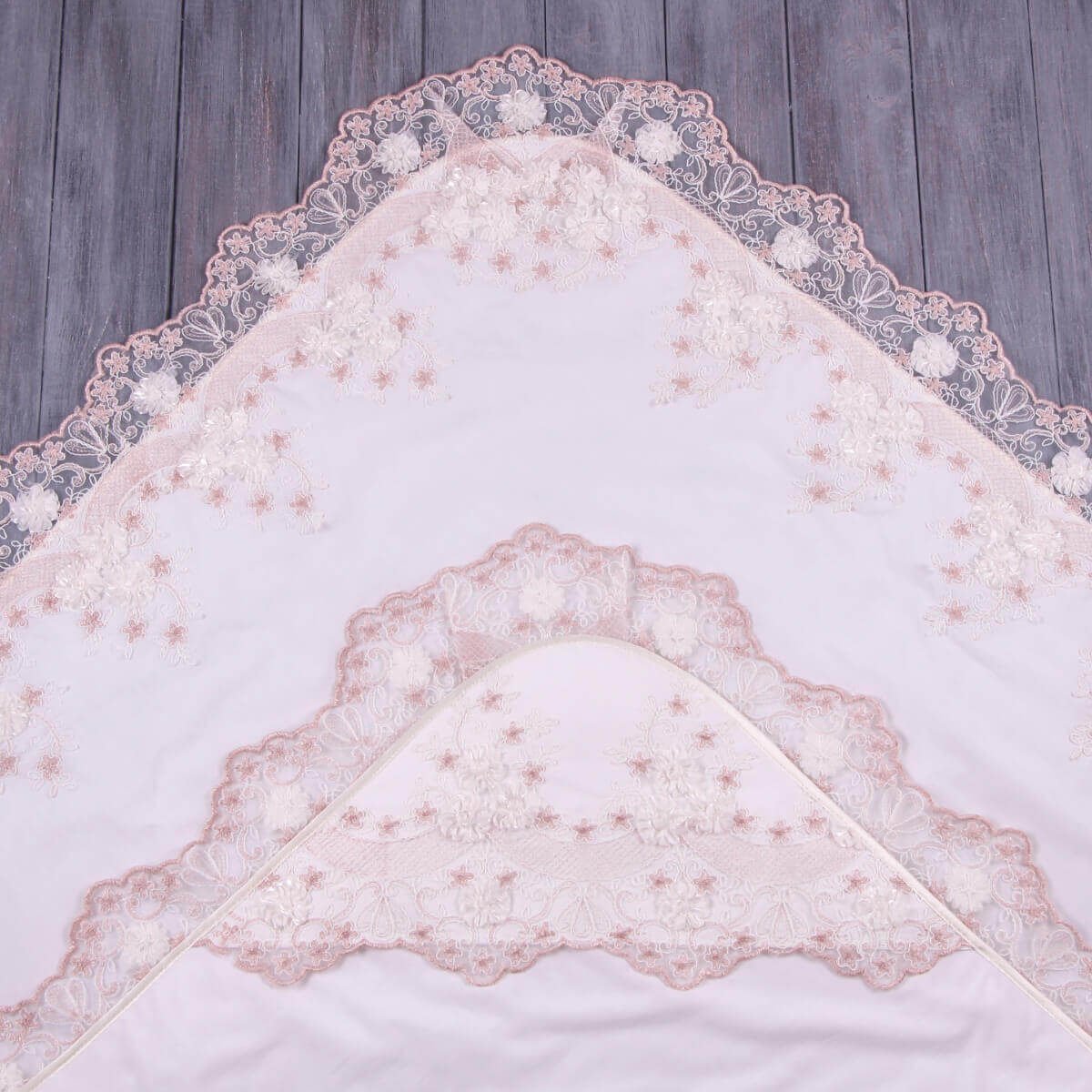 White lace baptism blanket on a wooden surface