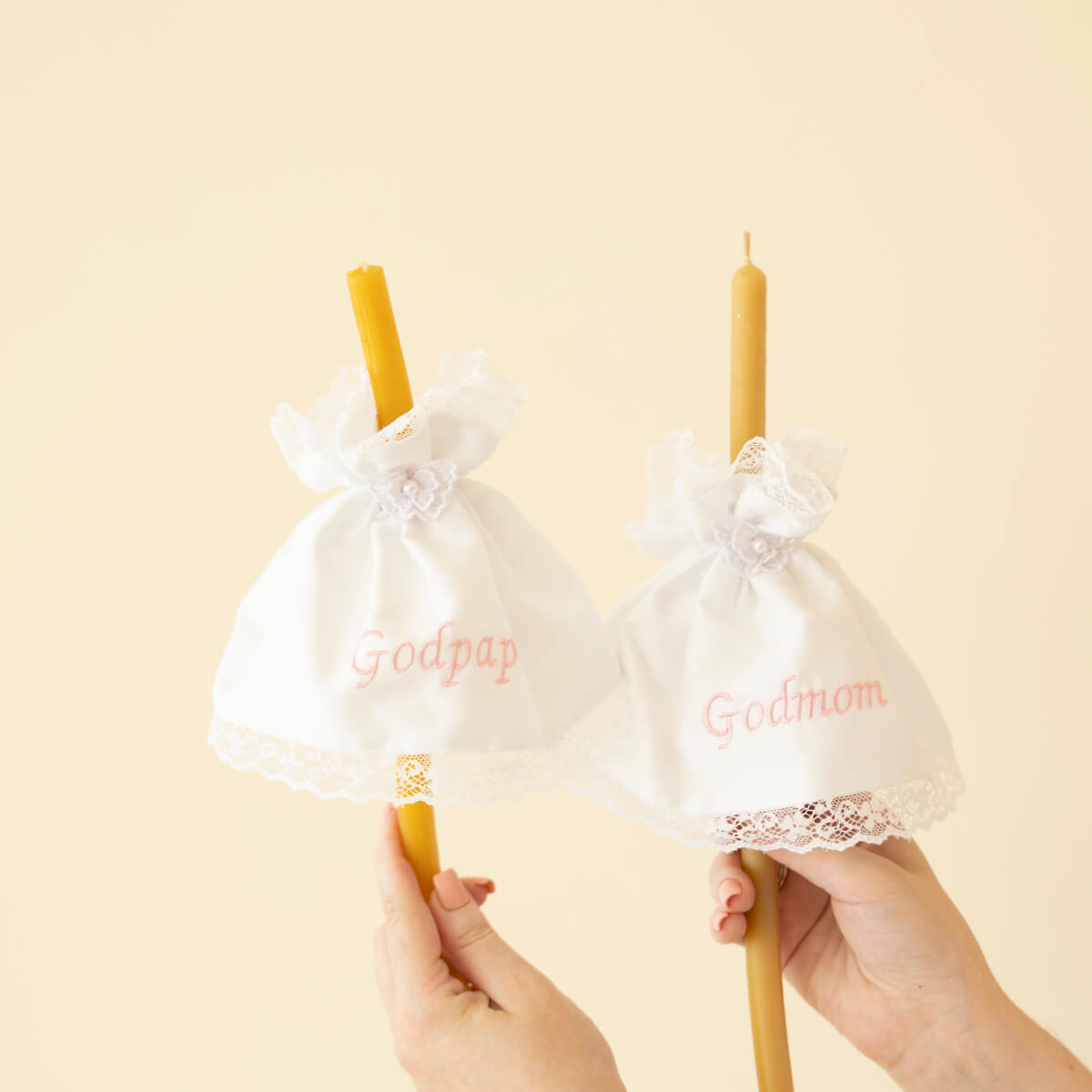 Two yellow candles in Candle Wraps with 'Godparent' and 'Godmother' text on a beige background.