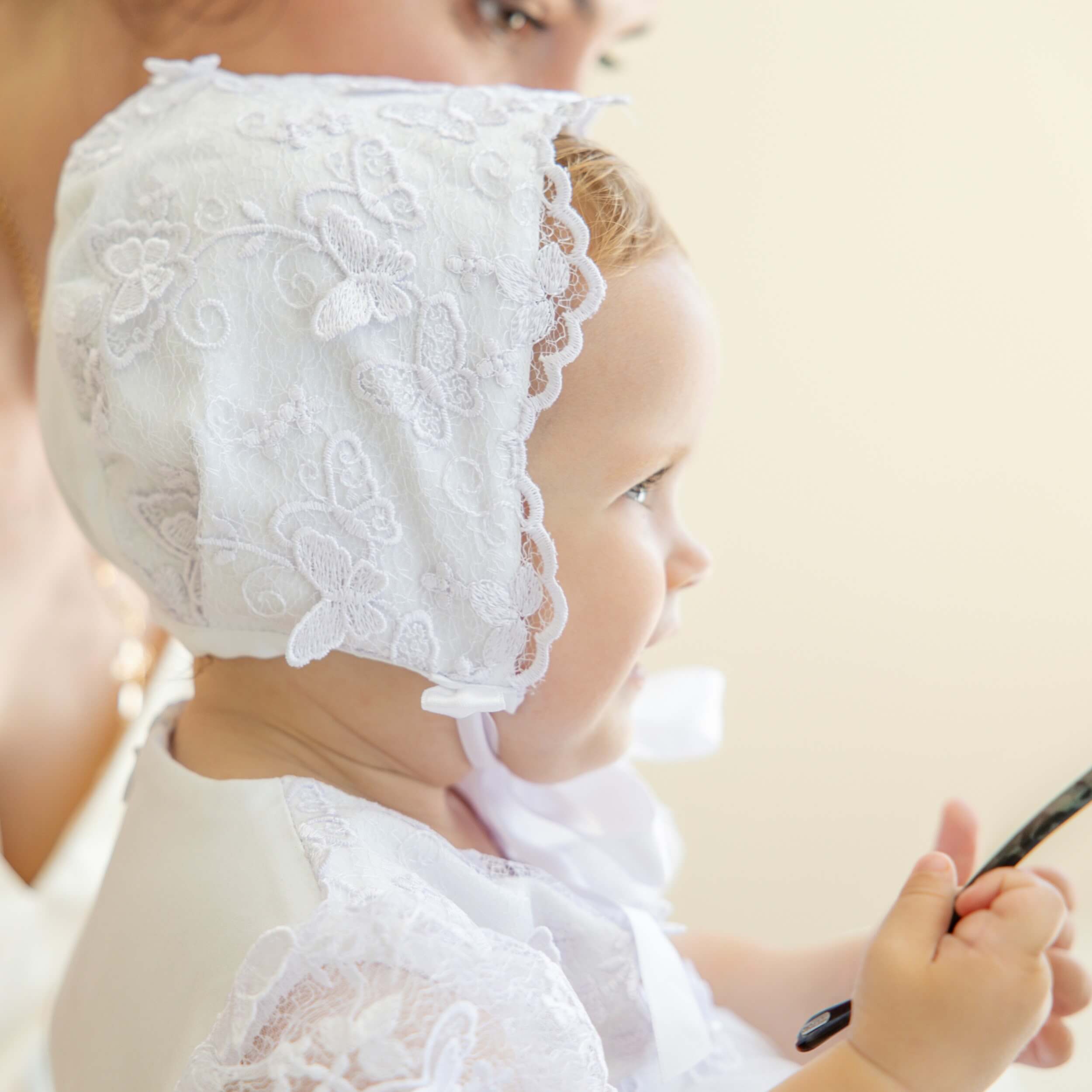 Baby wearing a lace baptism bonnet with a blurred background