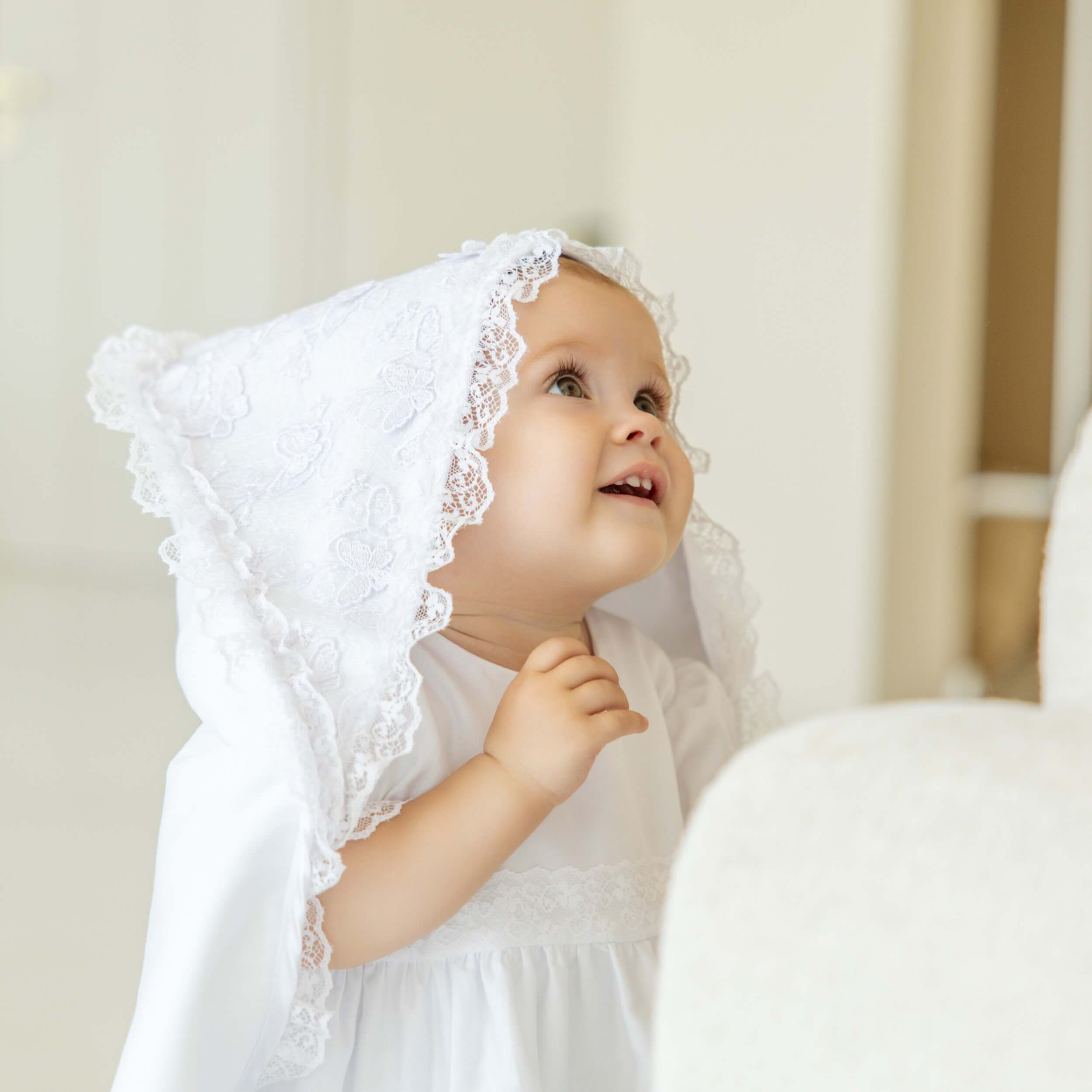 Baby in christening blanket against a neutral background