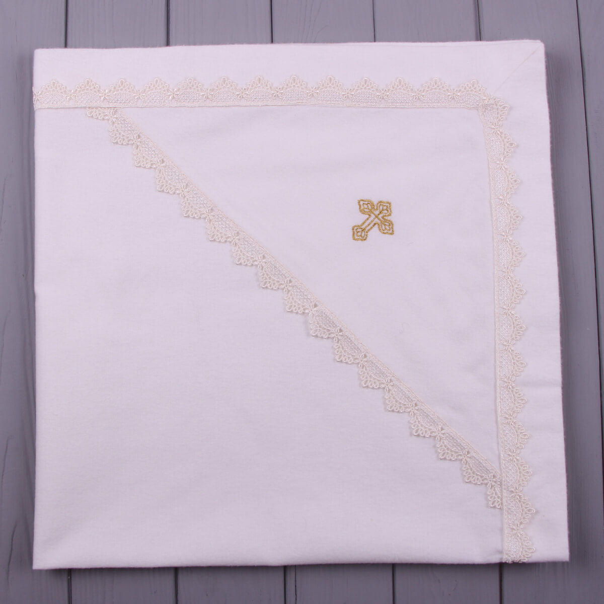 ivory baptism blanket with gold embroidery on a gray wooden surface