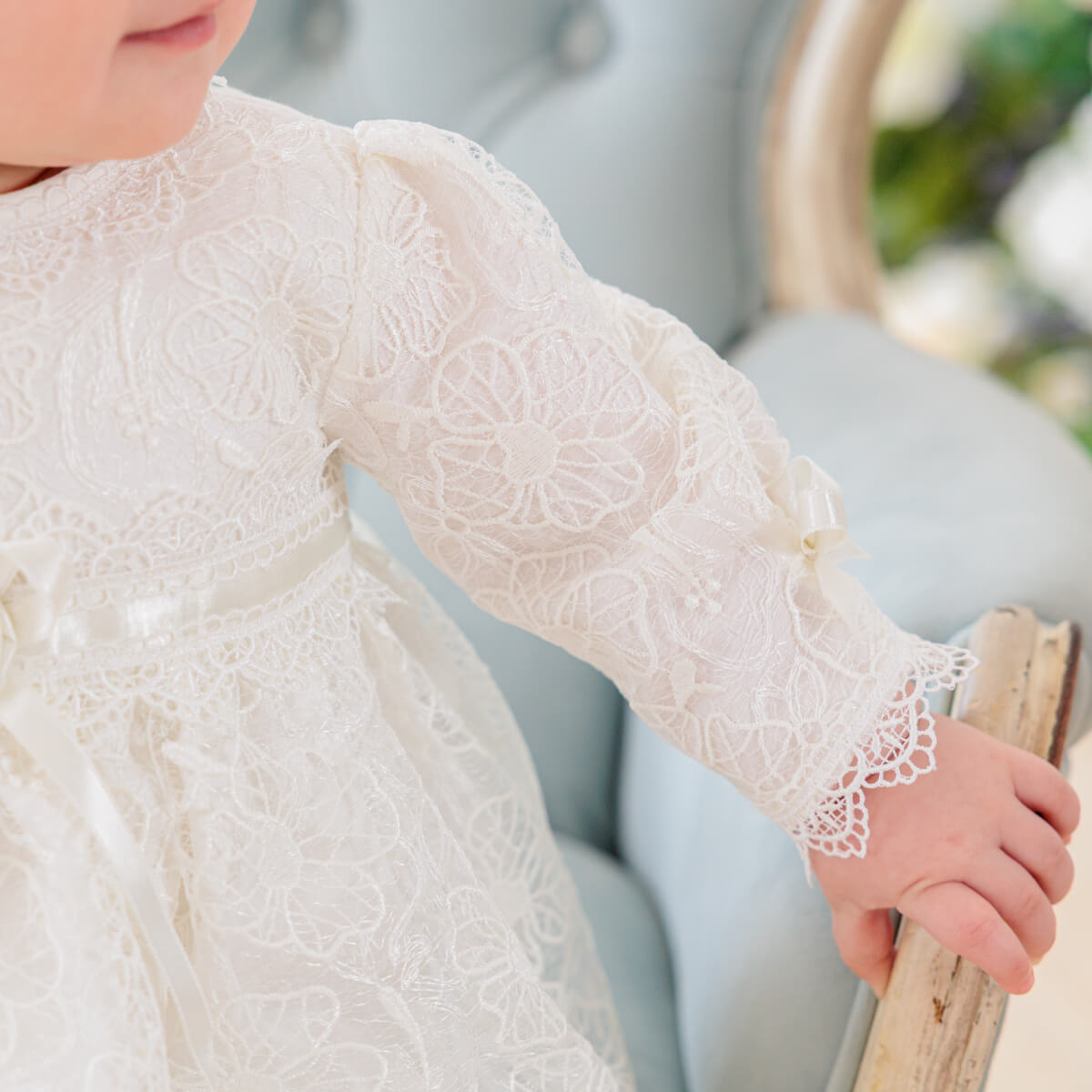 Close-up of a child wearing a Lace Baptism Dress with long sleeves.