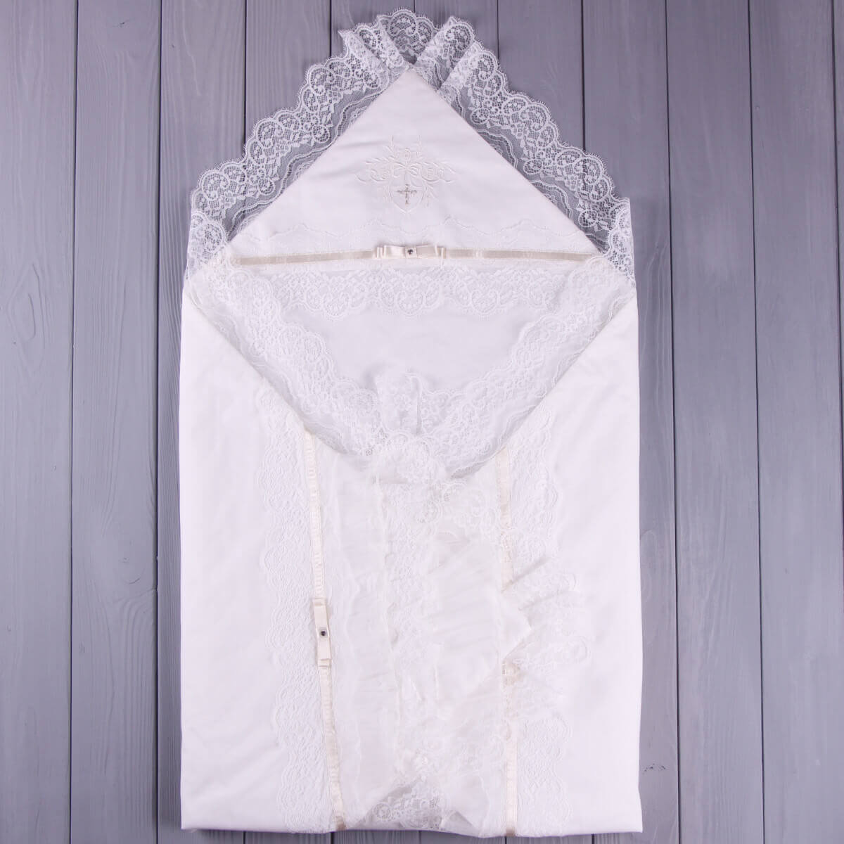 White baby blanket with lace trim on a wooden surface
