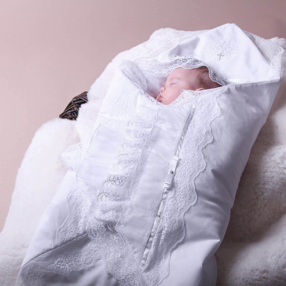 Newborn baby wrapped in a white lace blanket on a soft surface