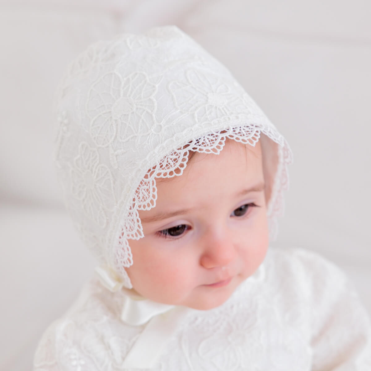 Baby wearing a tChristening Gown for Girls against a plain background