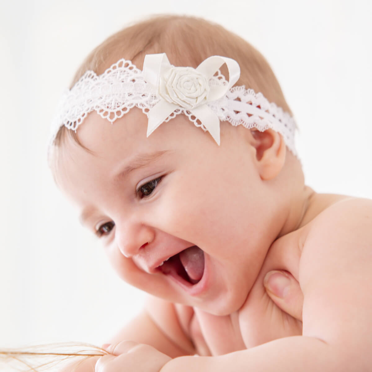 Girl wearing a white baby headband with a flower on a light background
