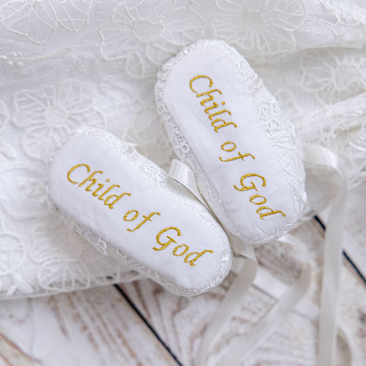 Baby Booties with 'Child of God' embroidery on a textured white background