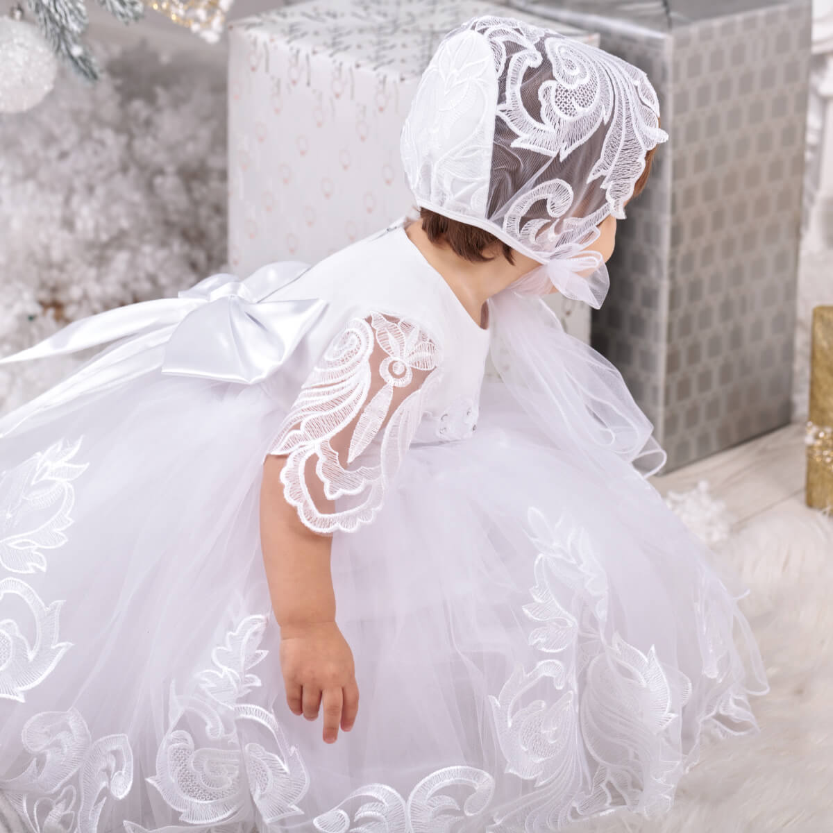 Baby in a White Baptism Dress and bonnet with decorative elements.