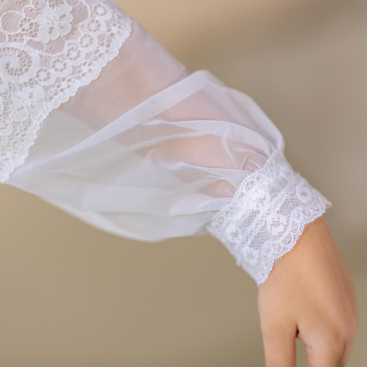Close-up of a white lace sleeve on a neutral background