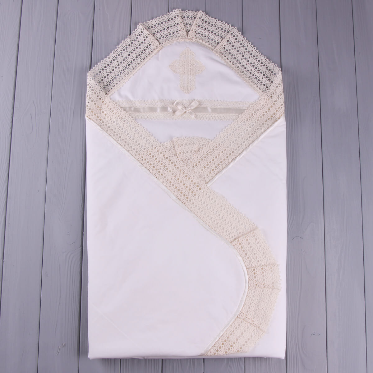 White baby blanket with lace trim on a wooden surface