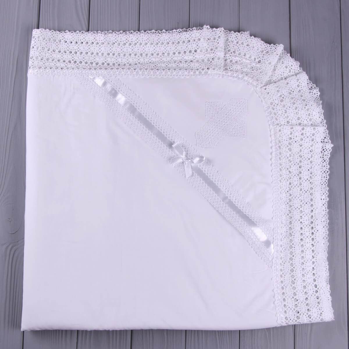 White lace-trimmed baptism blanket. on a wooden surface