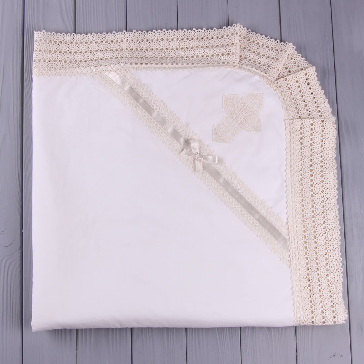 White blanket with beige crochet border on a wooden surface