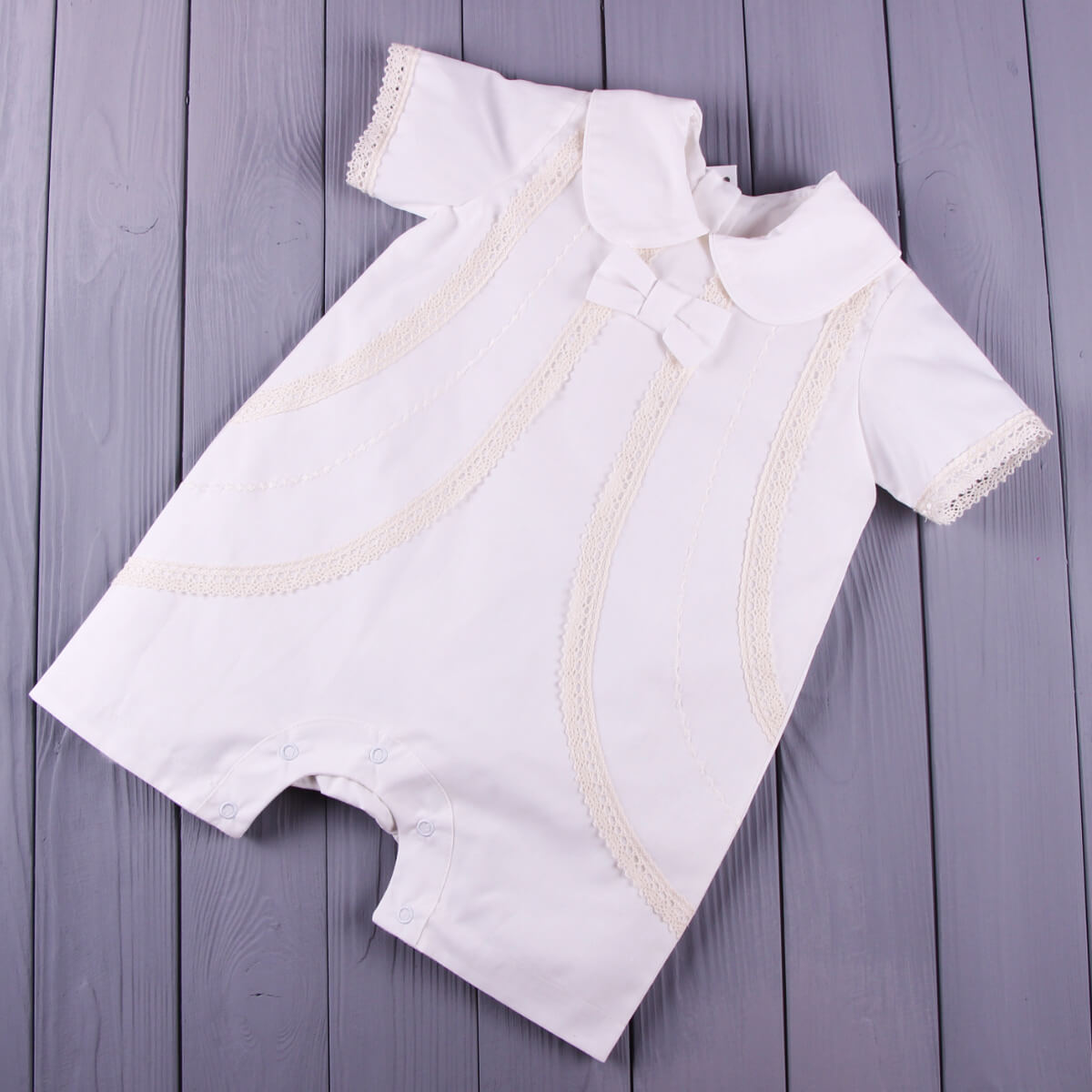 Baby Boy Christening Romper with lace trim on a wooden surface