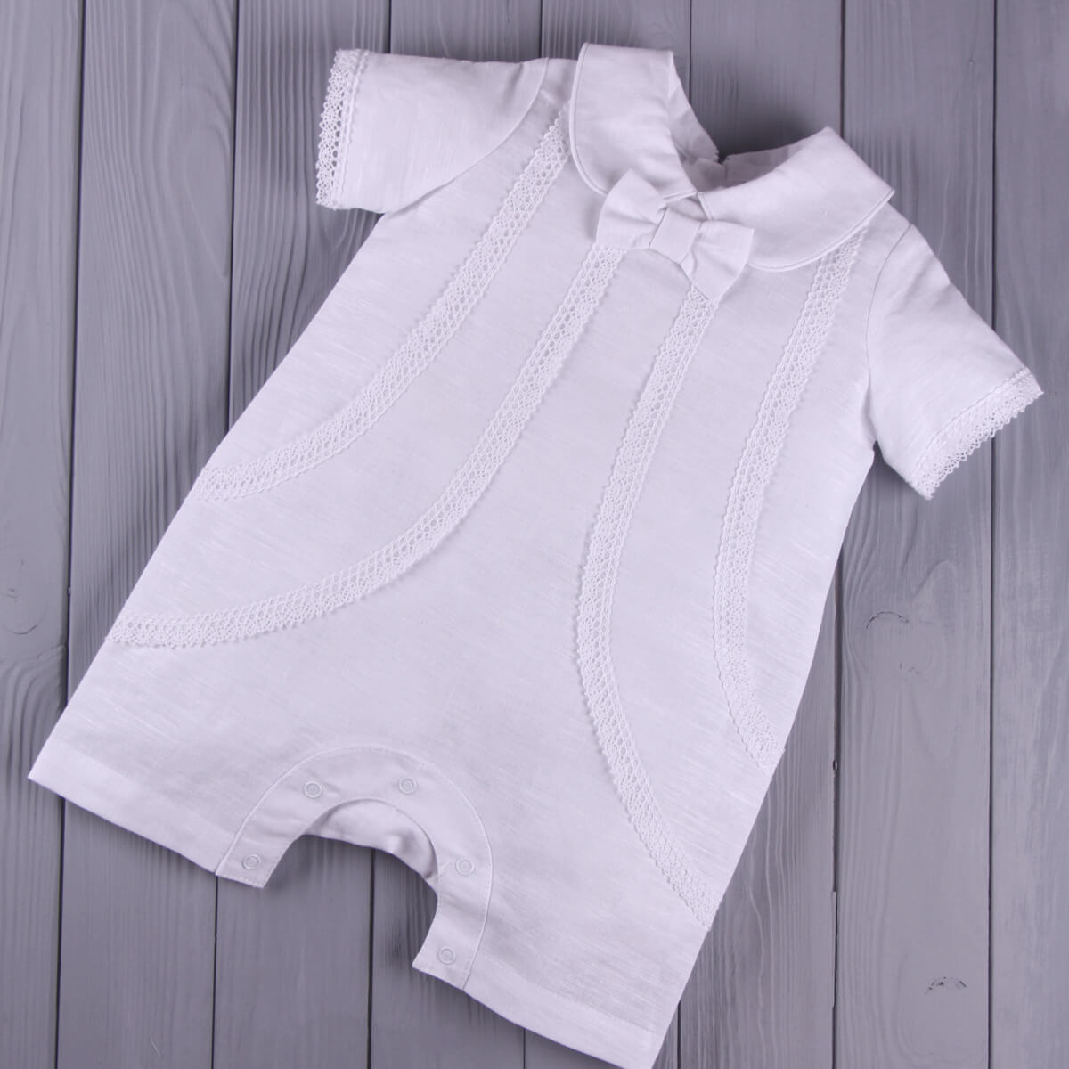 Baby Boy Christening Romper with lace details on a wooden surface