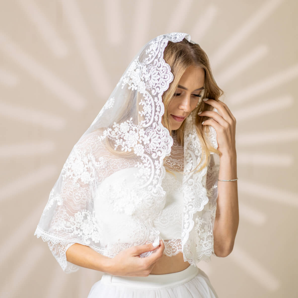 Woman wearing a  Church Mantilla over a white dress against a beige background