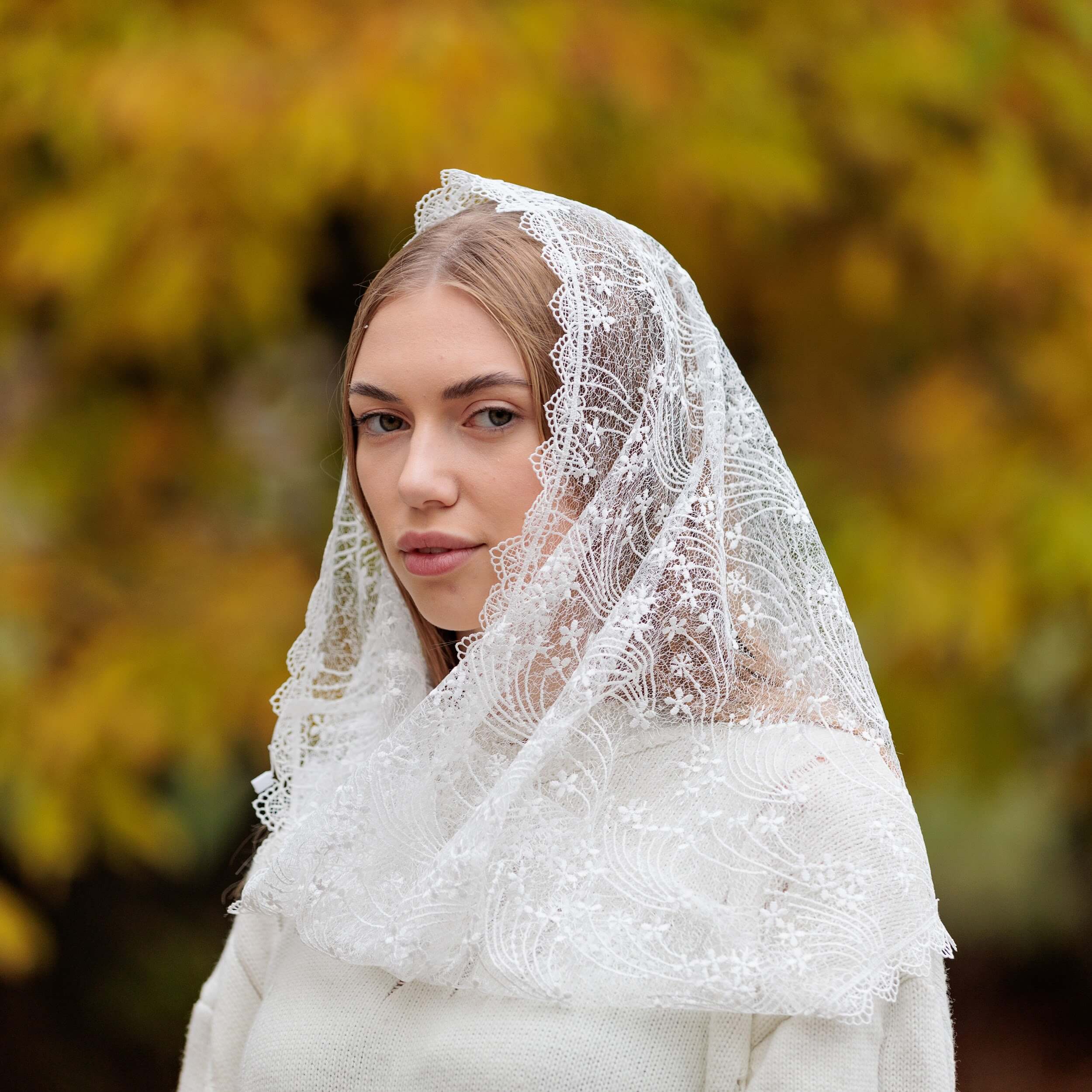 Woman wearing a Catholic Infinity Veil against a blurred natural background