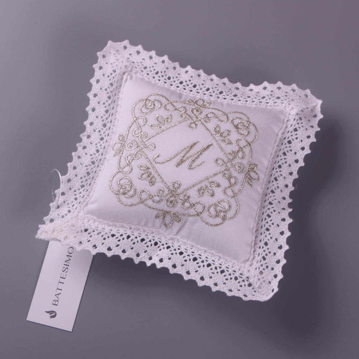 Baptism Ceremony Pillow with lace edge and embroidered design on a gray background, featuring a tag labeled 'Battesimo'.