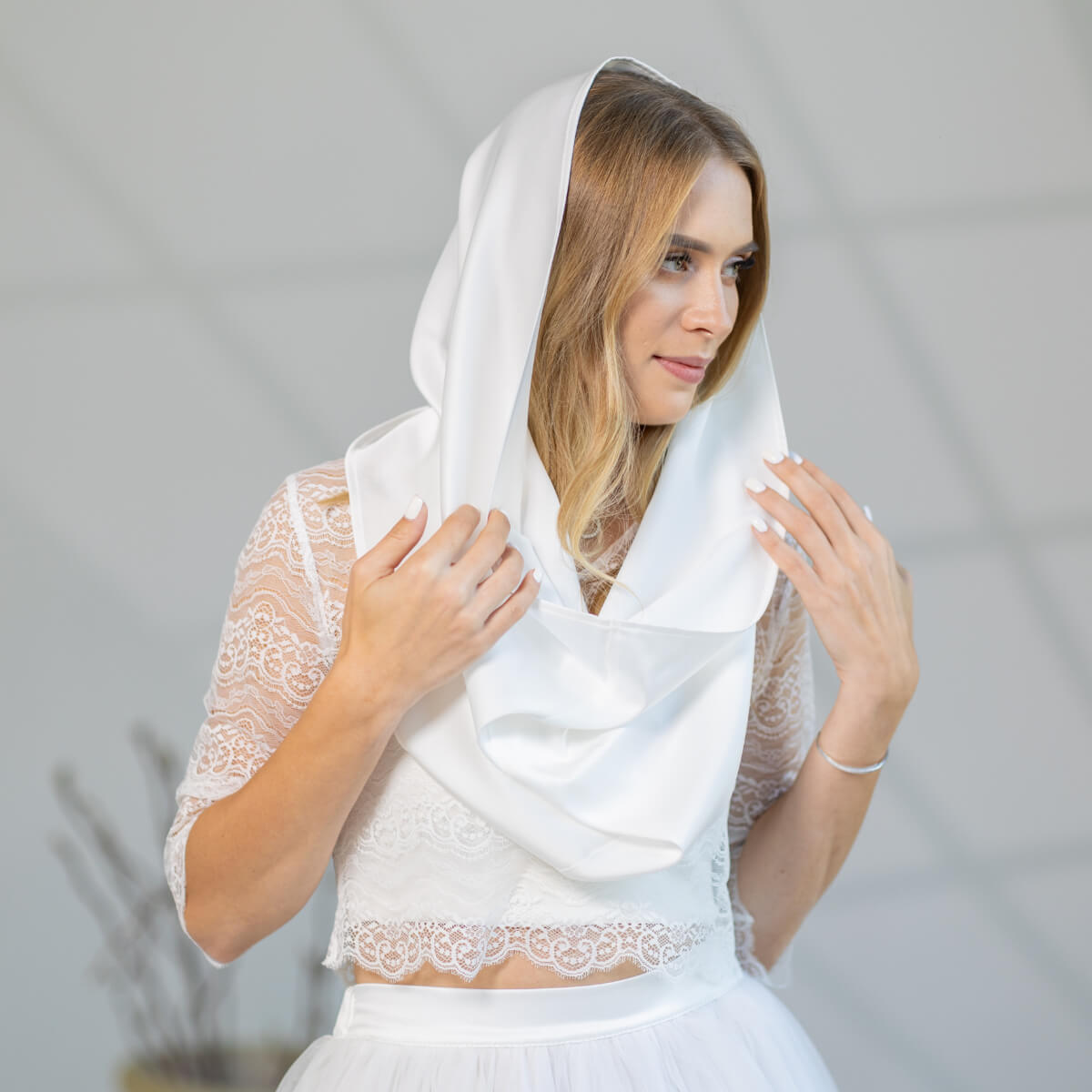 Woman wearing a Chapel Mantilla and lace top against a plain background