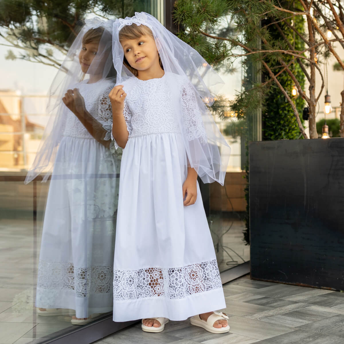 Two young girls in First Communion Cotton Dress with veils standing outdoors.