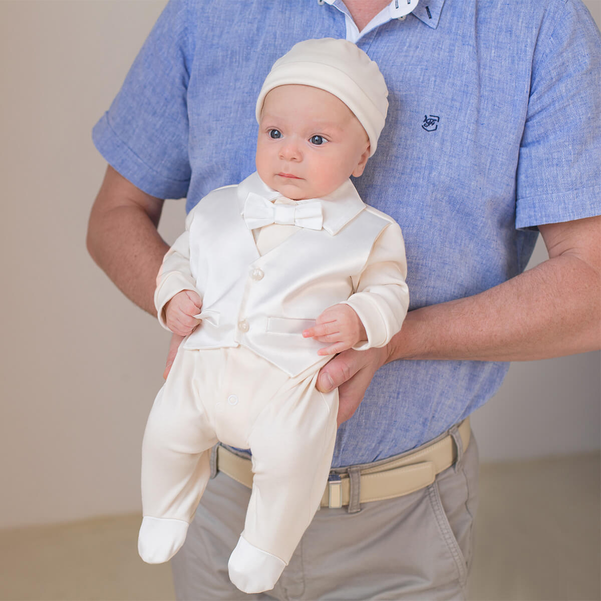 Baby in a Newborn Coming Home Romper being held by an adult against a plain background