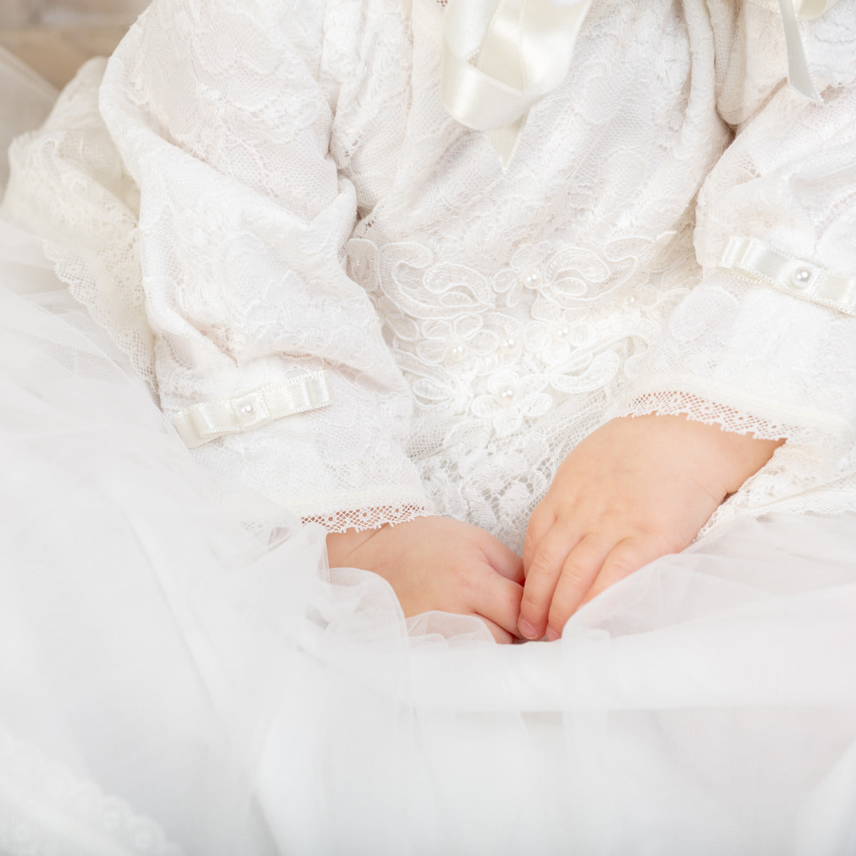 Close-up of a person wearing a Christening Gown for Girls with hands clasped together.