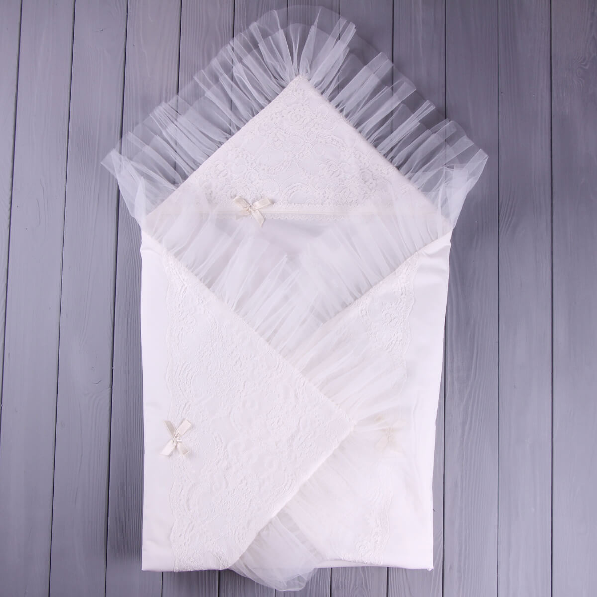 White lace christening blanket on a wooden surface