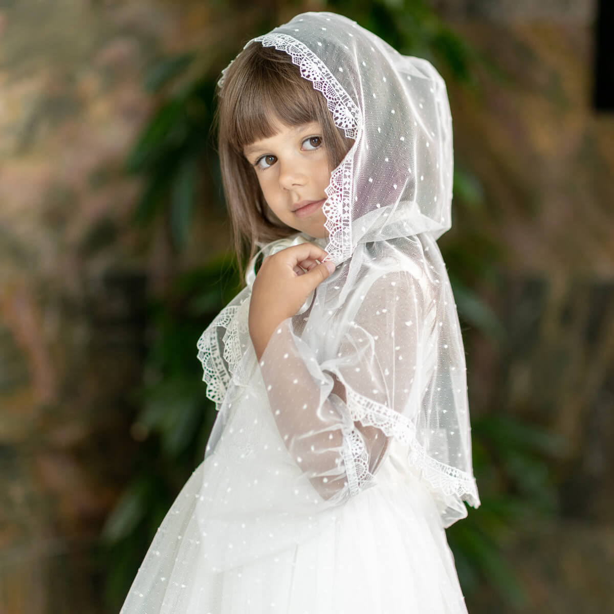Young girl wearing a First Communion Veil against a blurred natural background