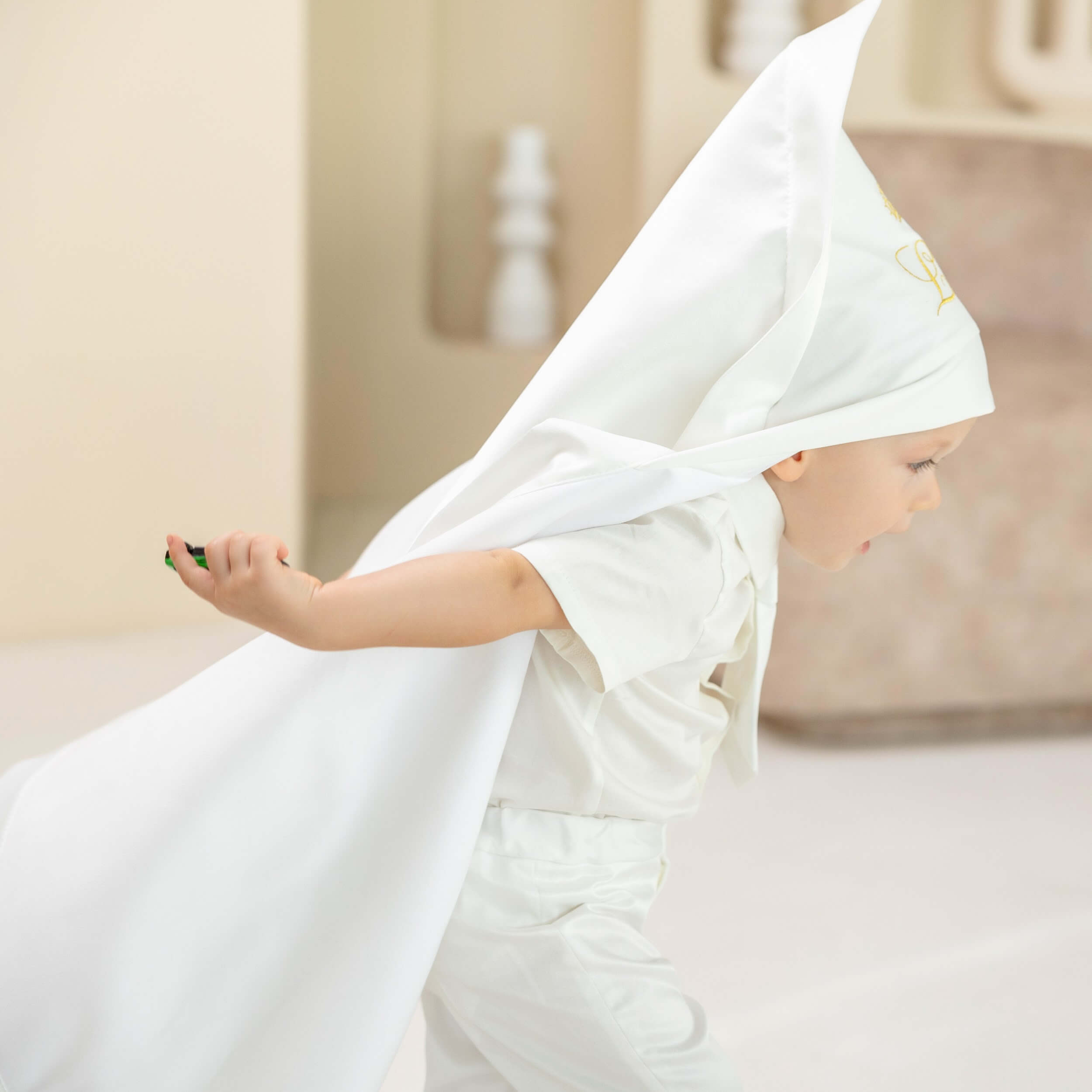 Child wearing a white baptism blanket and outfit, sitting on a couch.