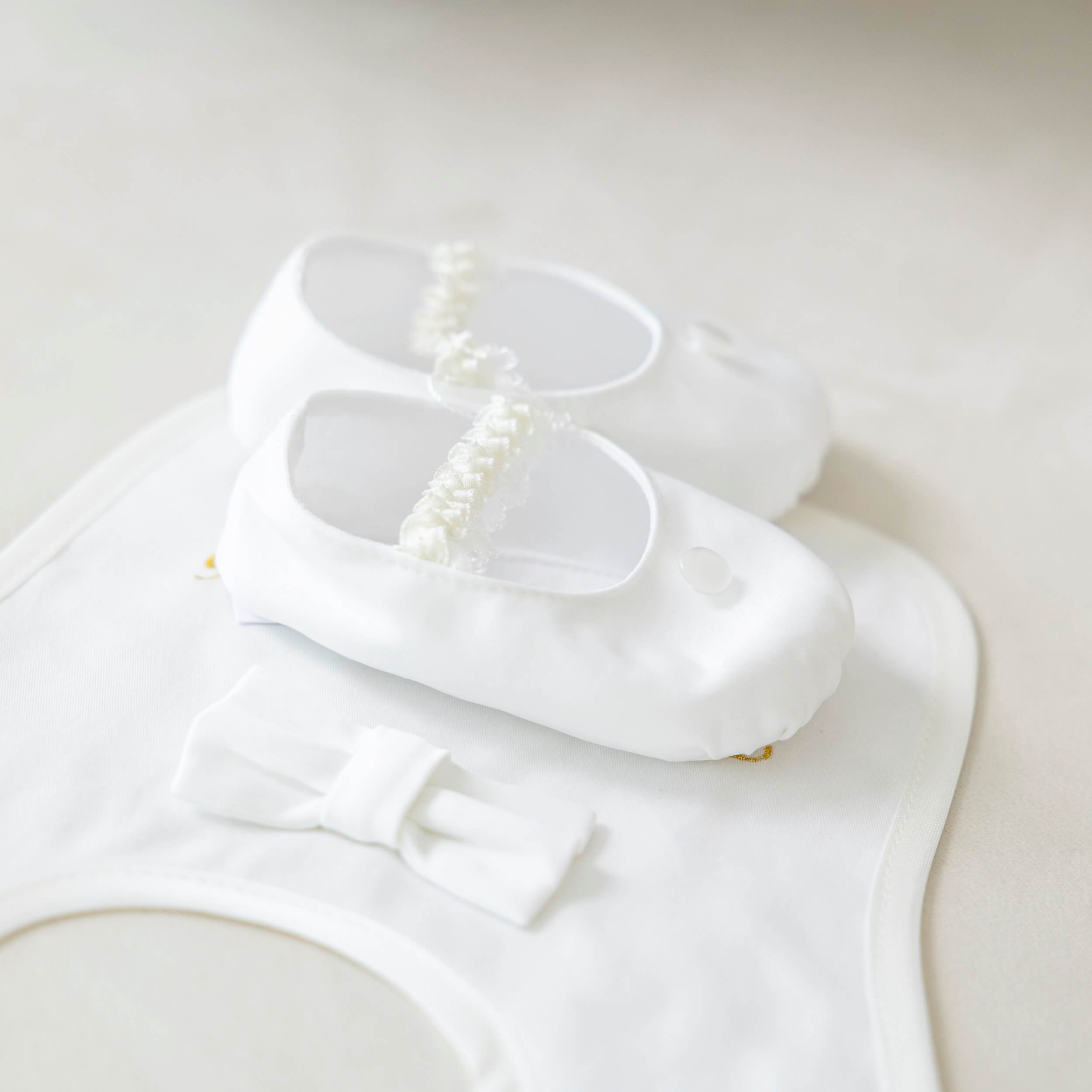  Christening Booties with a bow and pearl details on a white background