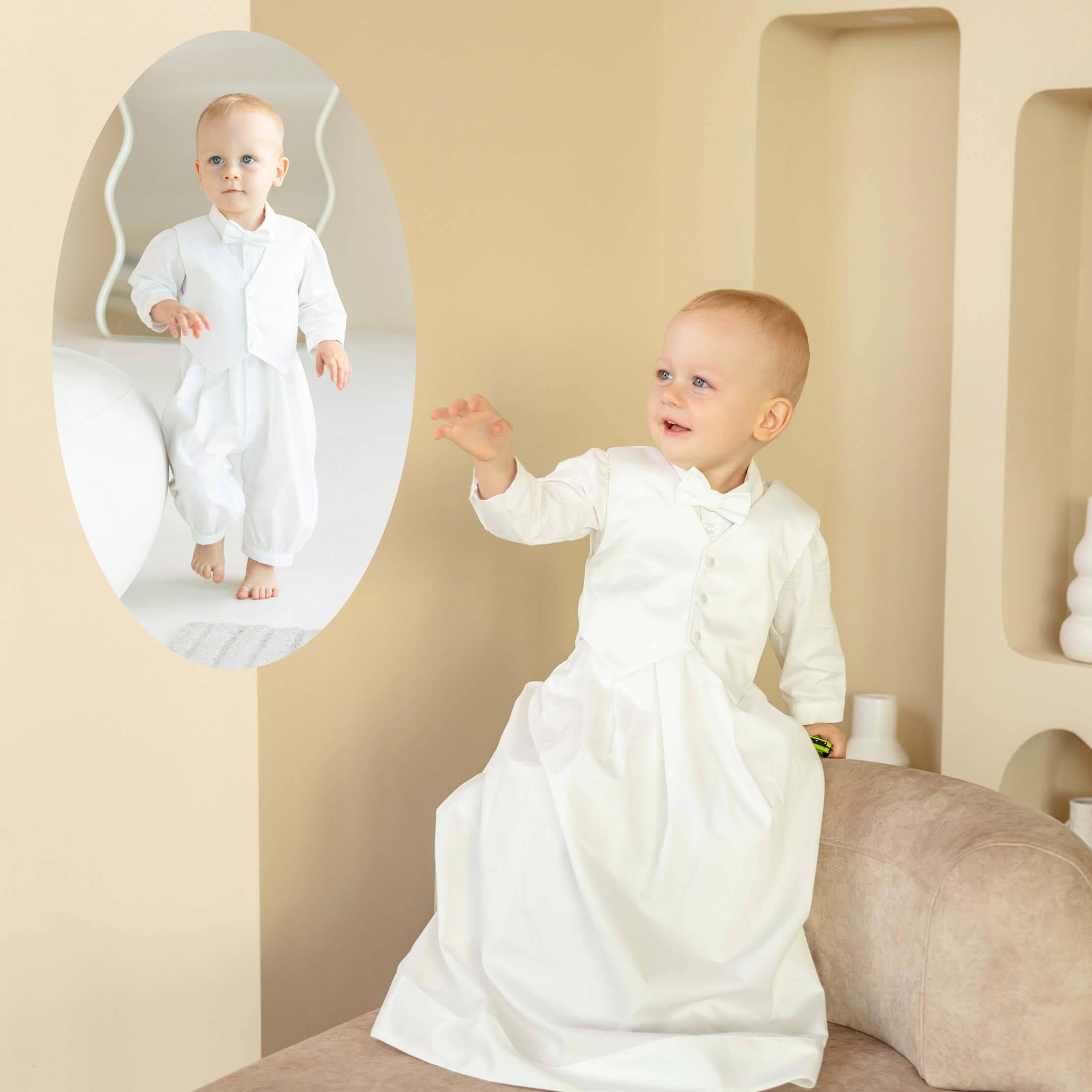 Baby in a white christening outfit sitting on a beige couch with a mirror reflection.