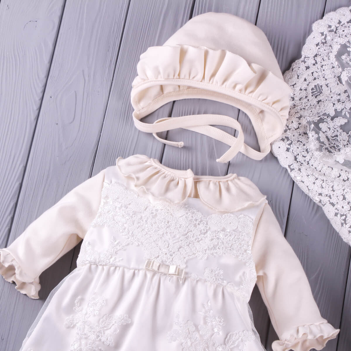 Coming Home Outfit  with lace details and matching bonnet on a wooden surface