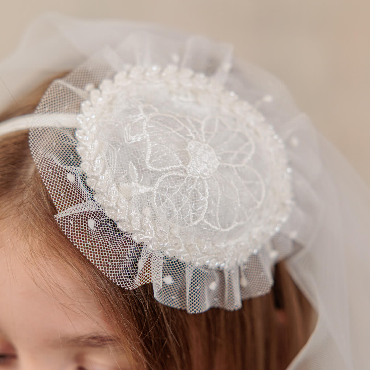 Close-up of a decorative headband with pearls and tulle on a neutral background