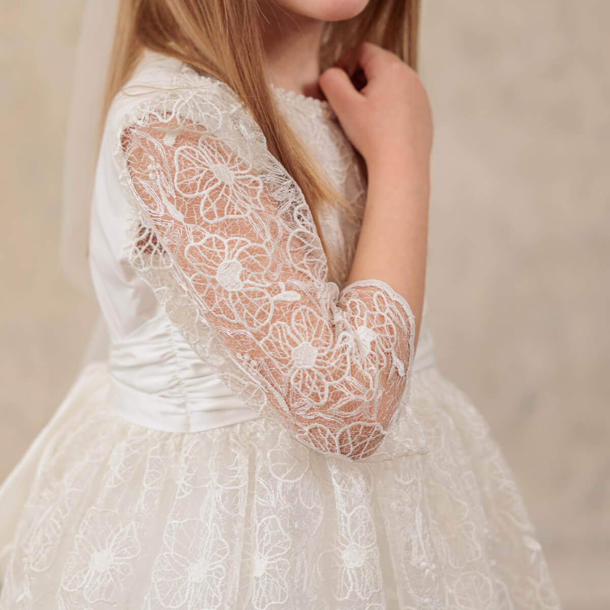 First Communion Dress with long sleeves on a neutral background