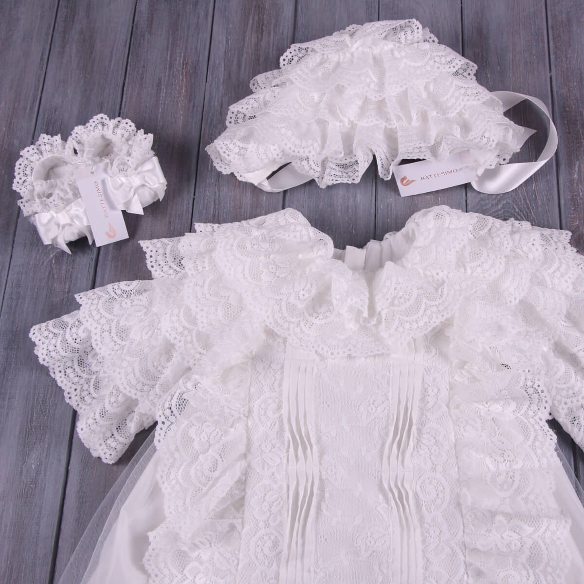 White lace baby outfit with headband on a wooden surface