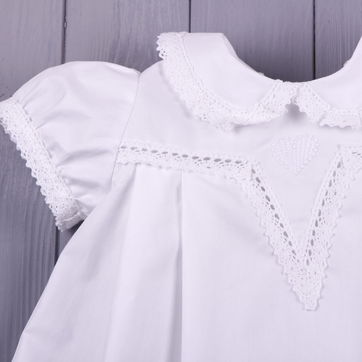 Girls Baptism Gown with lace collar against a wooden background