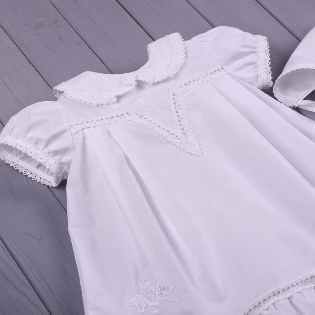Girls Baptism Gown with lace details on a wooden surface
