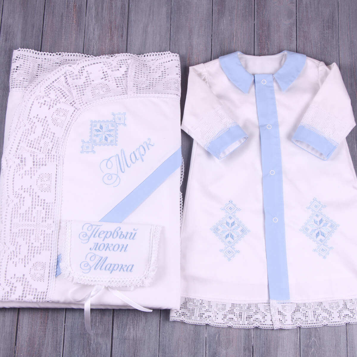 Baptism Gown with blue accents and a matching bag on a wooden surface