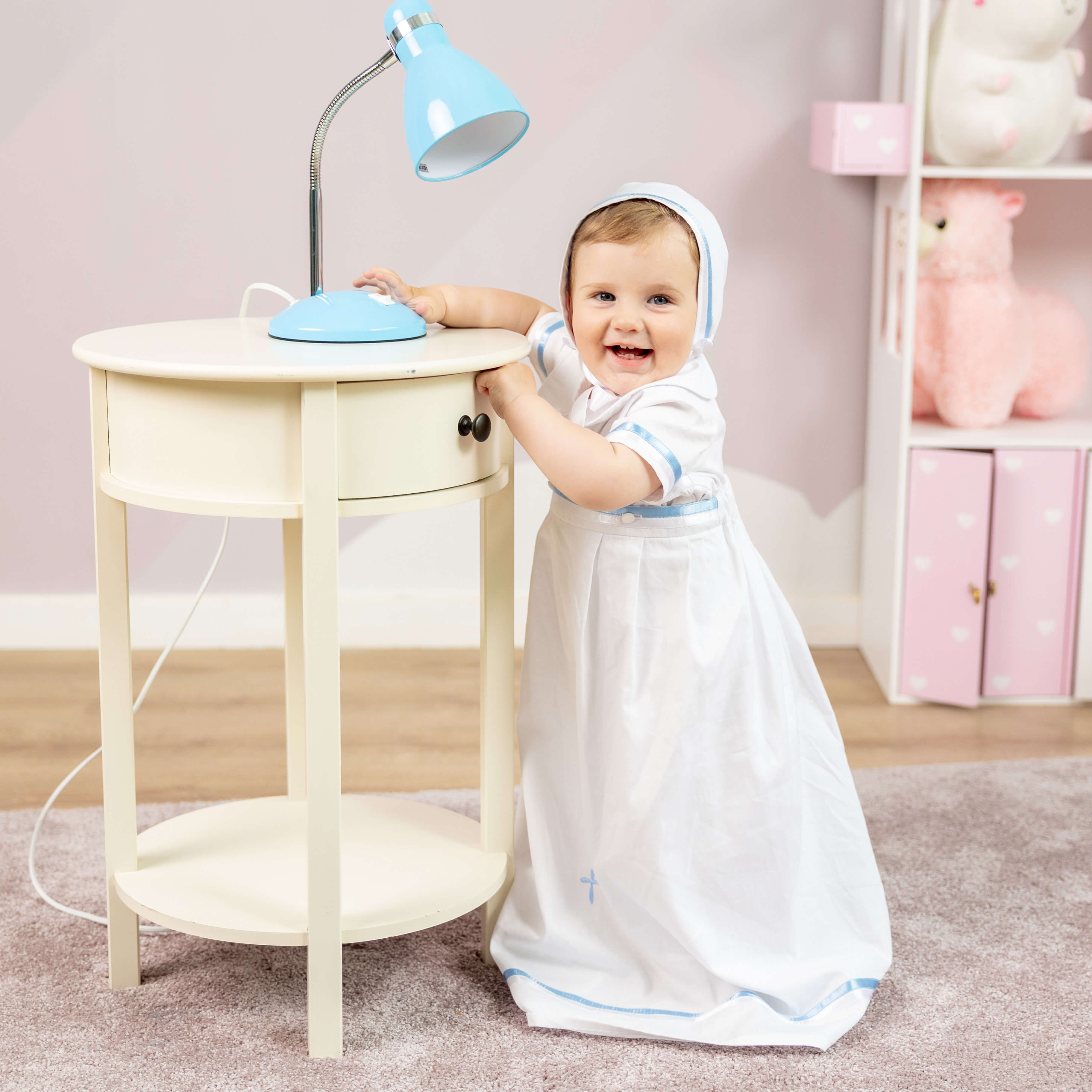 Child playing in Convertible Baptism Gown & Romper in a room with pink walls and toys.