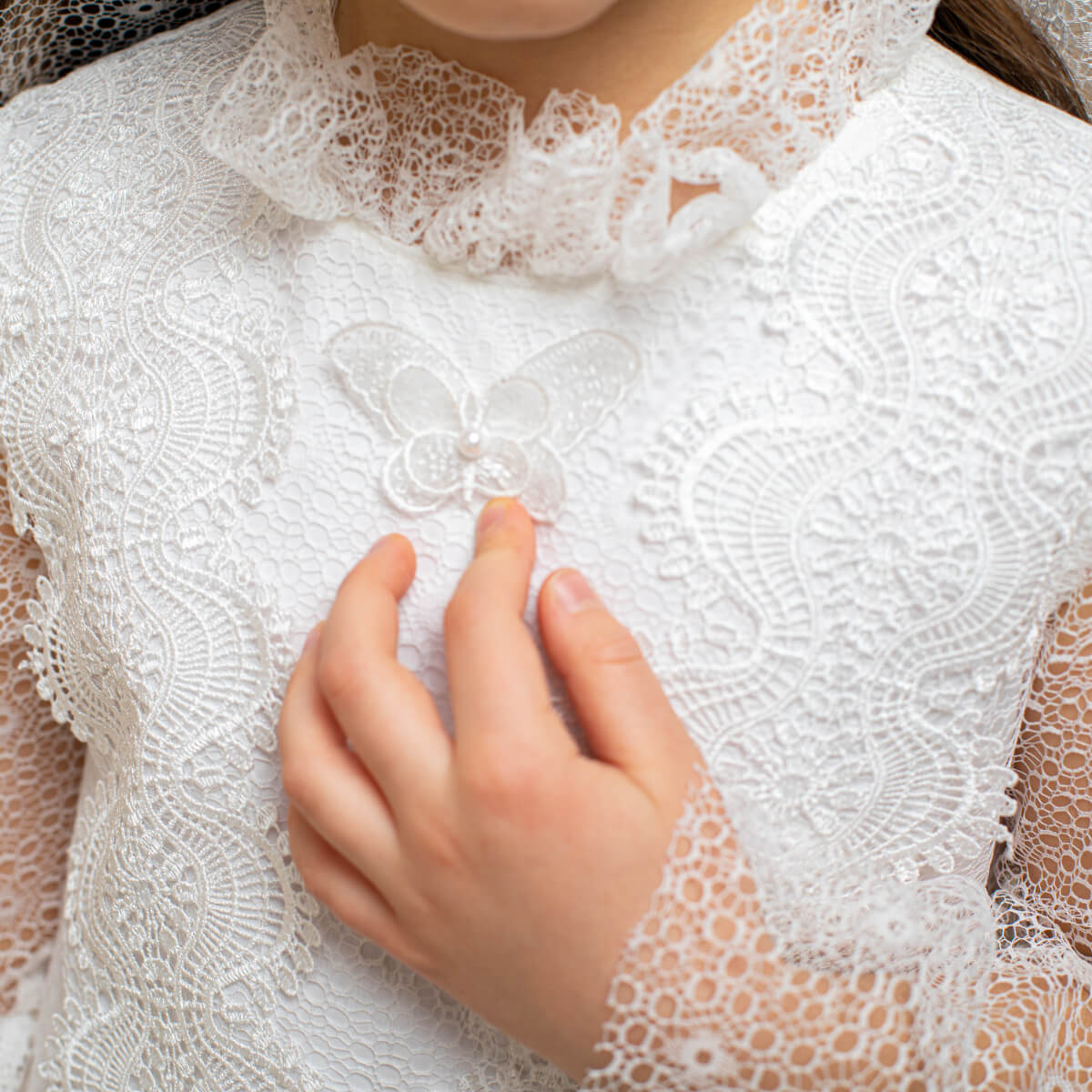 Close-up of a person wearing a white lace garment with a hand touching the fabric.