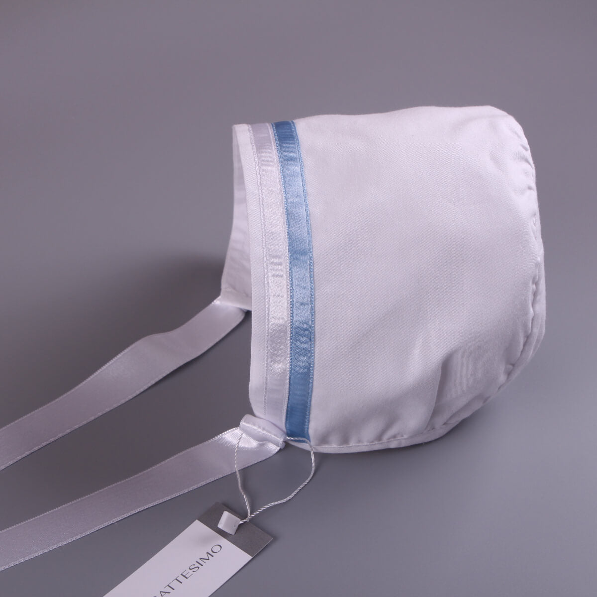 Boy Christening Bonnet with blue trim on a gray background, featuring a visible brand tag.