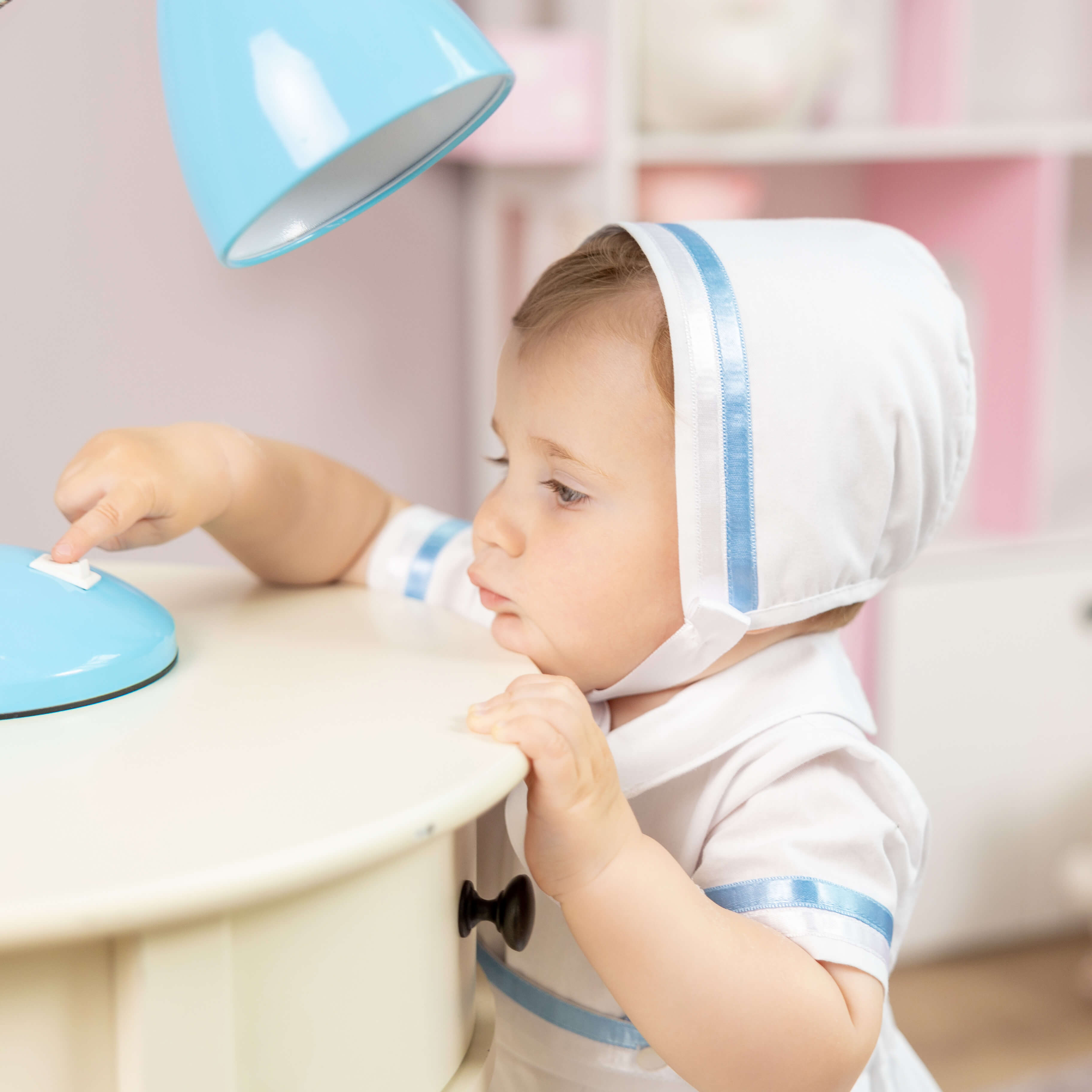 Child playing with a toy kitchen set in the Boy Christening Bonnet