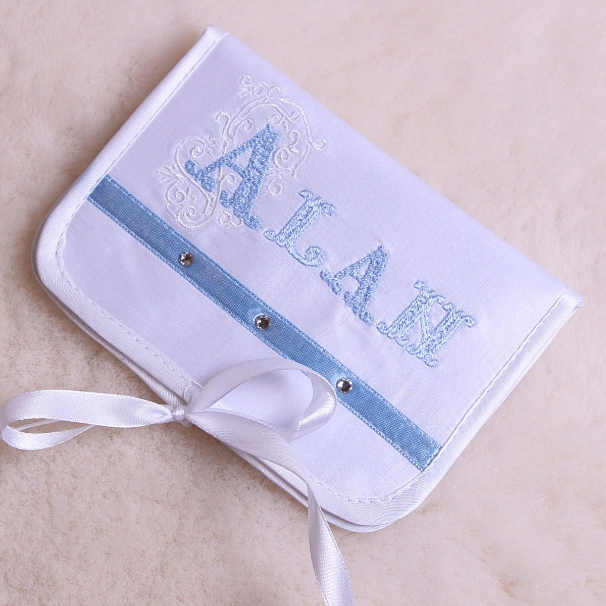 First Curl Keepsake Box with blue ribbon and embroidered name on a beige background