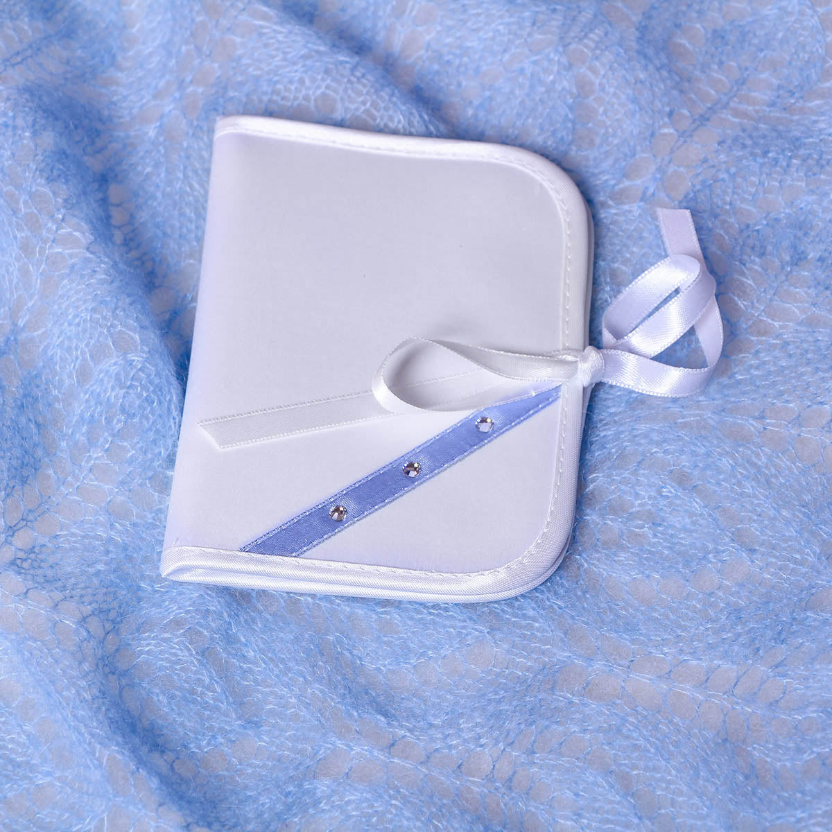 First Curl Keepsake Box with a blue ribbon on a blue textured fabric background