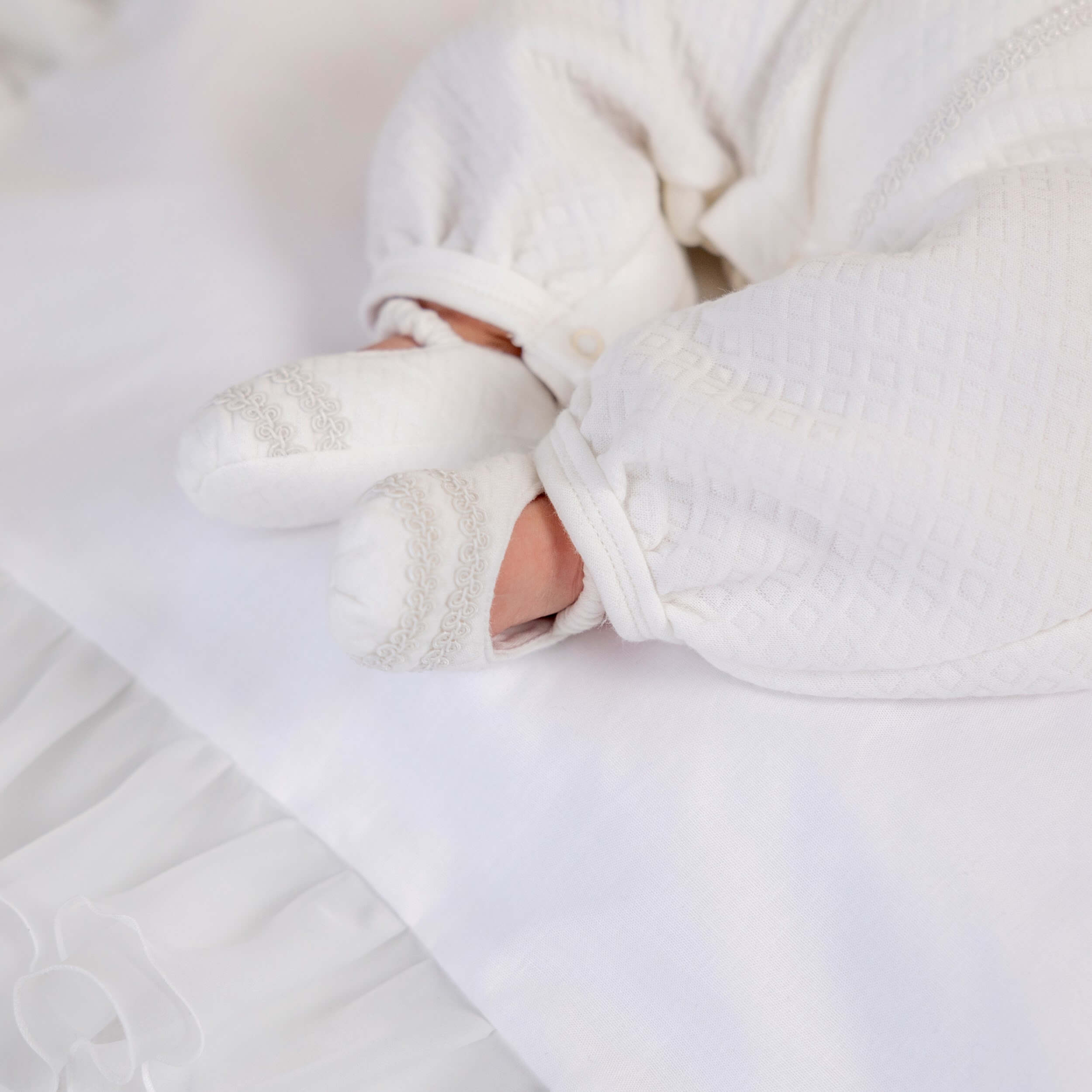 Close-up of a baby Baby Boy Christening Romper in white blankets and socks on a white background