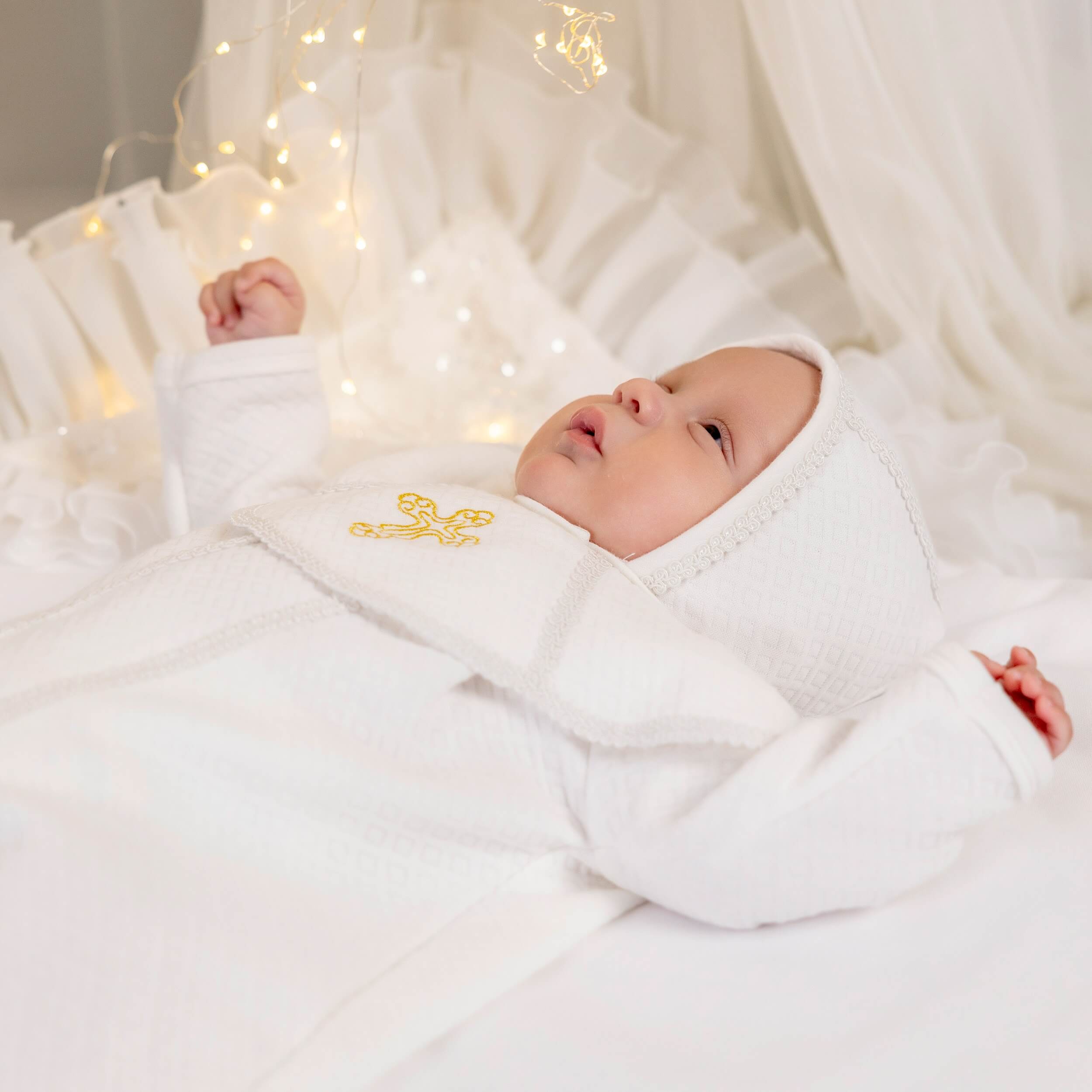 Newborn baby wrapped in Baby Boy Christening Romper with a soft glow in the background