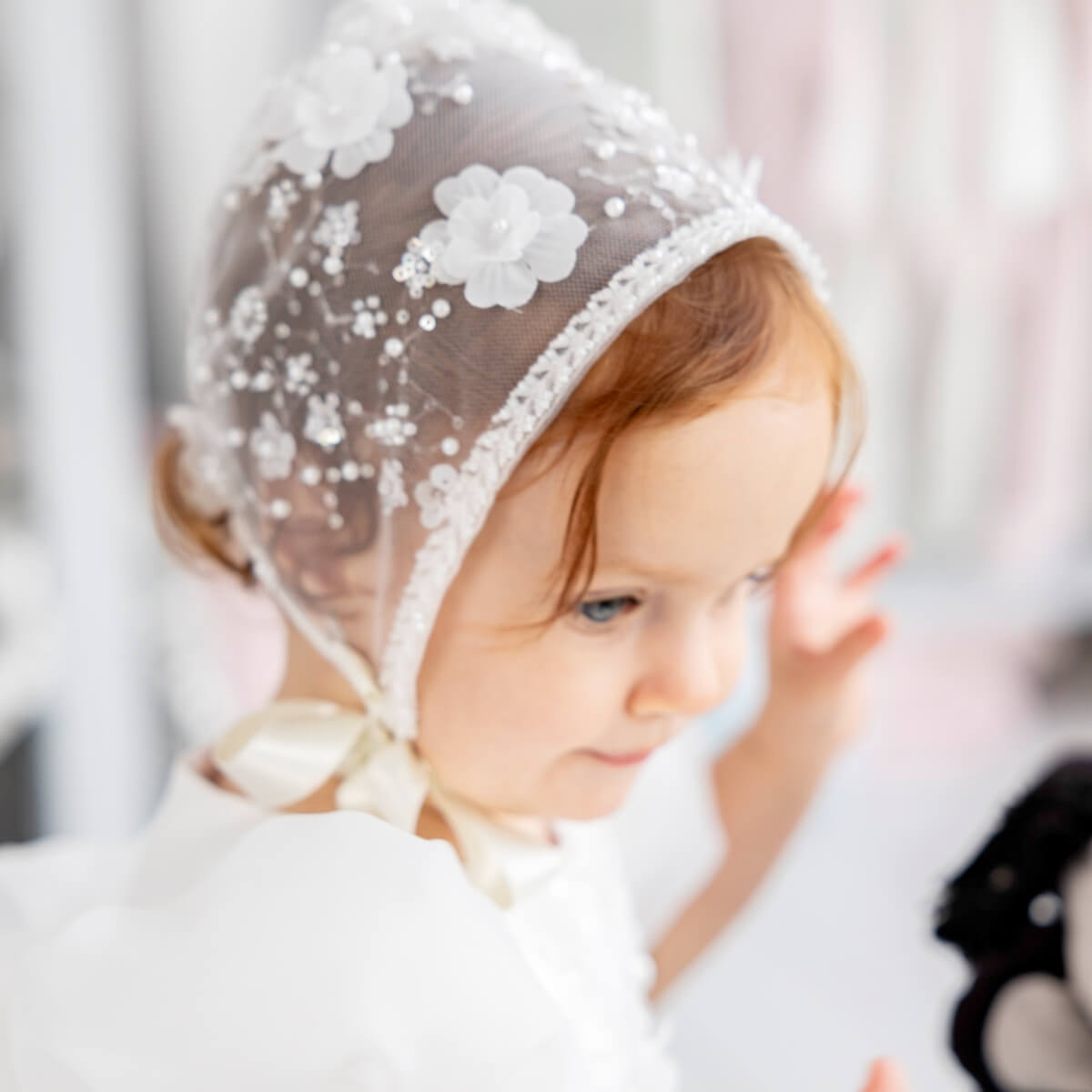 Child wearing a wLace Christening Bonnet with floral details.
