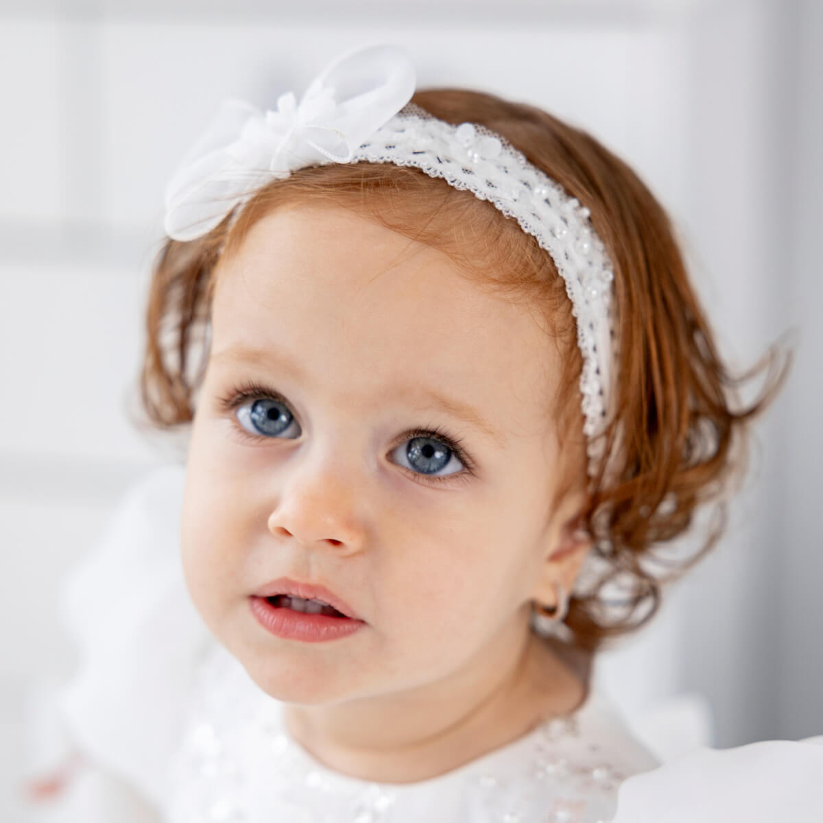 Girl wearing a baby headband with a bow on a light background